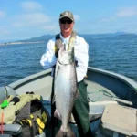 A man in black sunglasses holding the fish in the boat